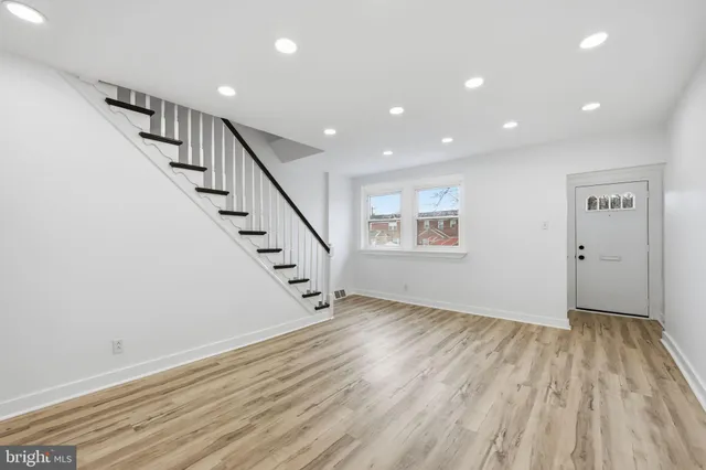 a view of an empty room with wooden floor and stairs