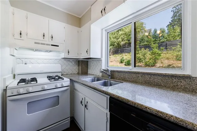 a kitchen with granite countertop a sink a stove and cabinets