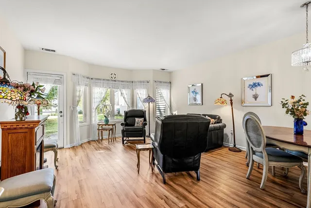 a living room with furniture and a dining table with wooden floor