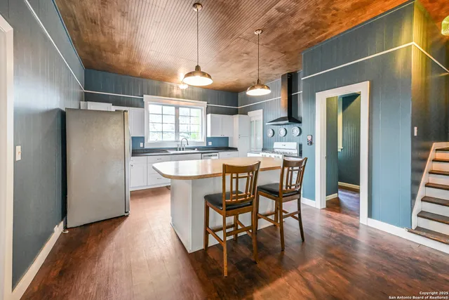 a kitchen with stainless steel appliances a dining table chairs refrigerator and sink