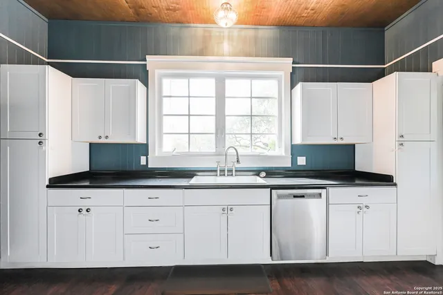 a kitchen with granite countertop a sink and a white cabinets