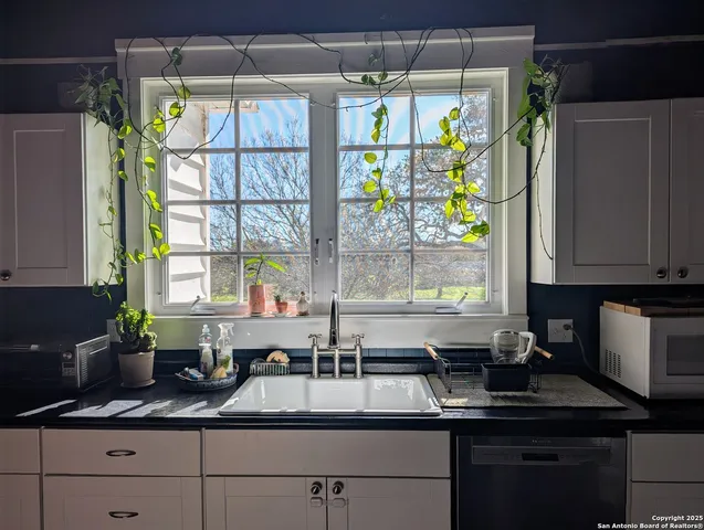 a kitchen with stainless steel appliances granite countertop a sink a counter space and a window
