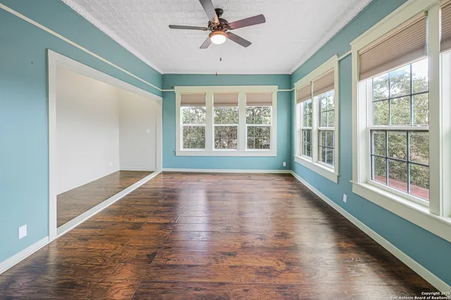 a view of empty room with wooden floor and fan