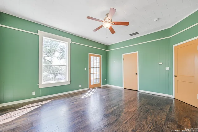a view of an empty room with window and wooden floor