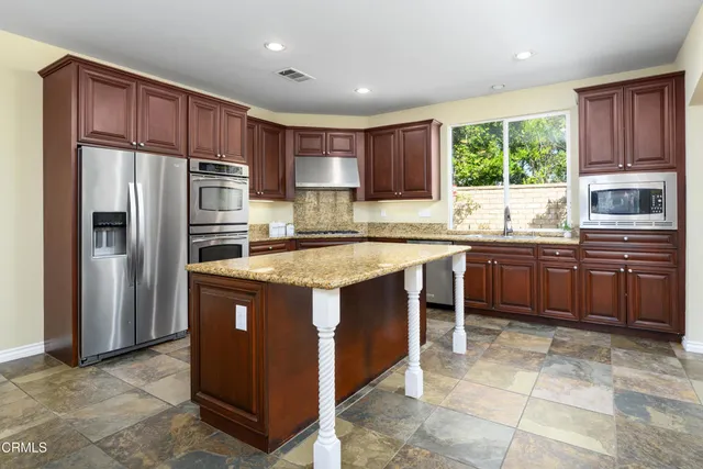 a kitchen with granite countertop wooden cabinets stainless steel appliances and a sink