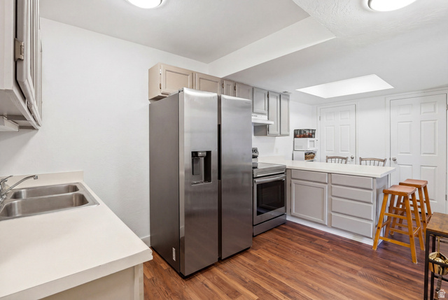 88 West 50 South, Unit P10 Centerville, UT 84014 - Photo 8 of 20 Kitchen with stainless steel appliances, a peninsula, light countertops, dark wood-style flooring, and a breakfast bar area