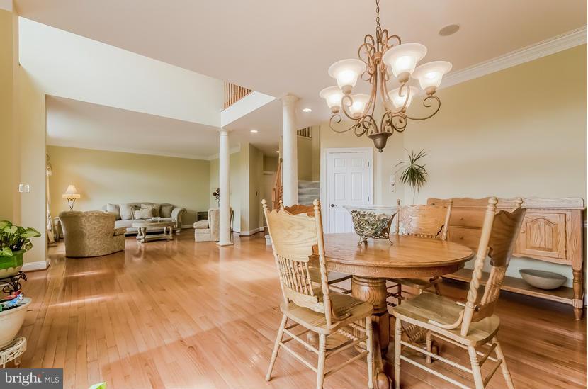 615 Sand Road Severn, MD 21144 - Photo 5 of 30 a dining room with wooden floor a chandelier a glass table and chairs