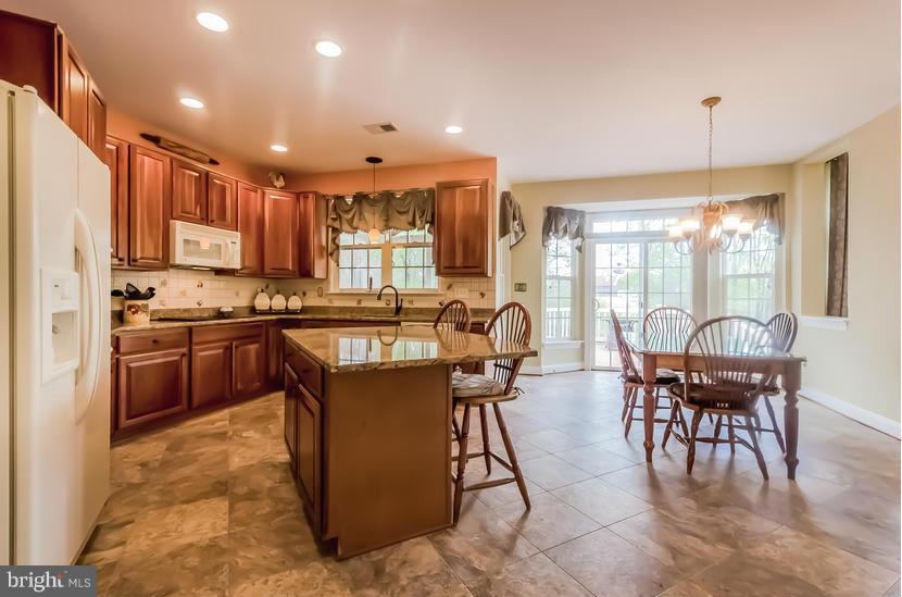 615 Sand Road Severn, MD 21144 - Photo 8 of 30 a kitchen with stainless steel appliances granite countertop a stove top oven a sink dishwasher a dining table and chairs with wooden floor