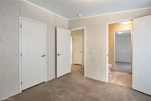a view of an empty room with closet and a bathroom