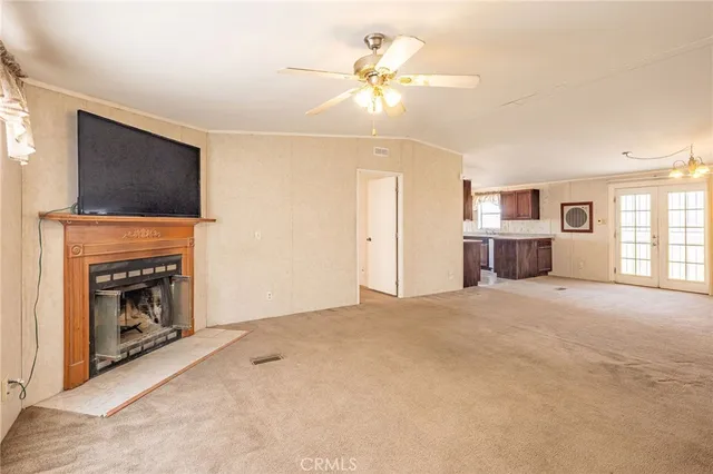 a view of empty room with a fireplace and a ceiling fan
