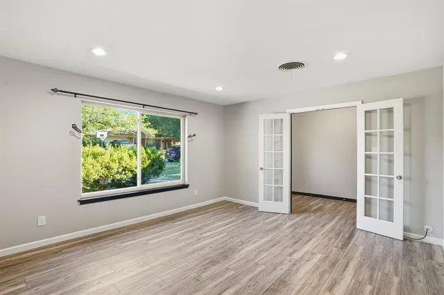 a view of an empty room with wooden floor and a window