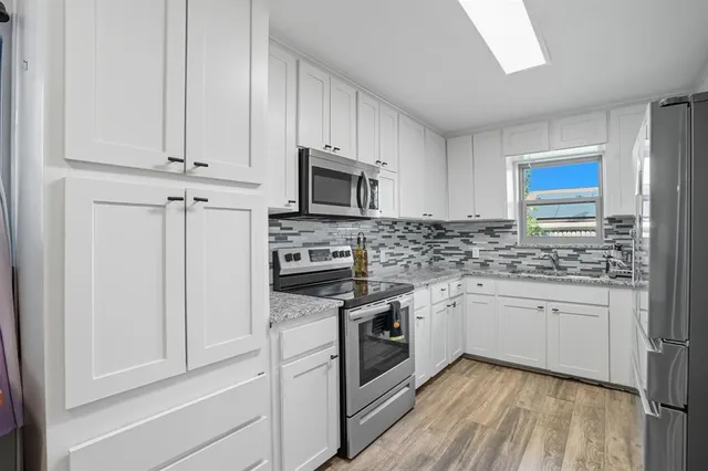 a kitchen with stainless steel appliances granite countertop white cabinets stove a sink and dishwasher