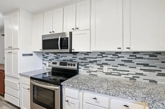 a kitchen with granite countertop white cabinets and appliances