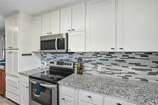 a kitchen with granite countertop a stove a microwave and sink