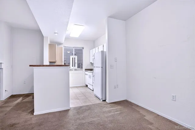 a view of a kitchen with refrigerator and white cabinets