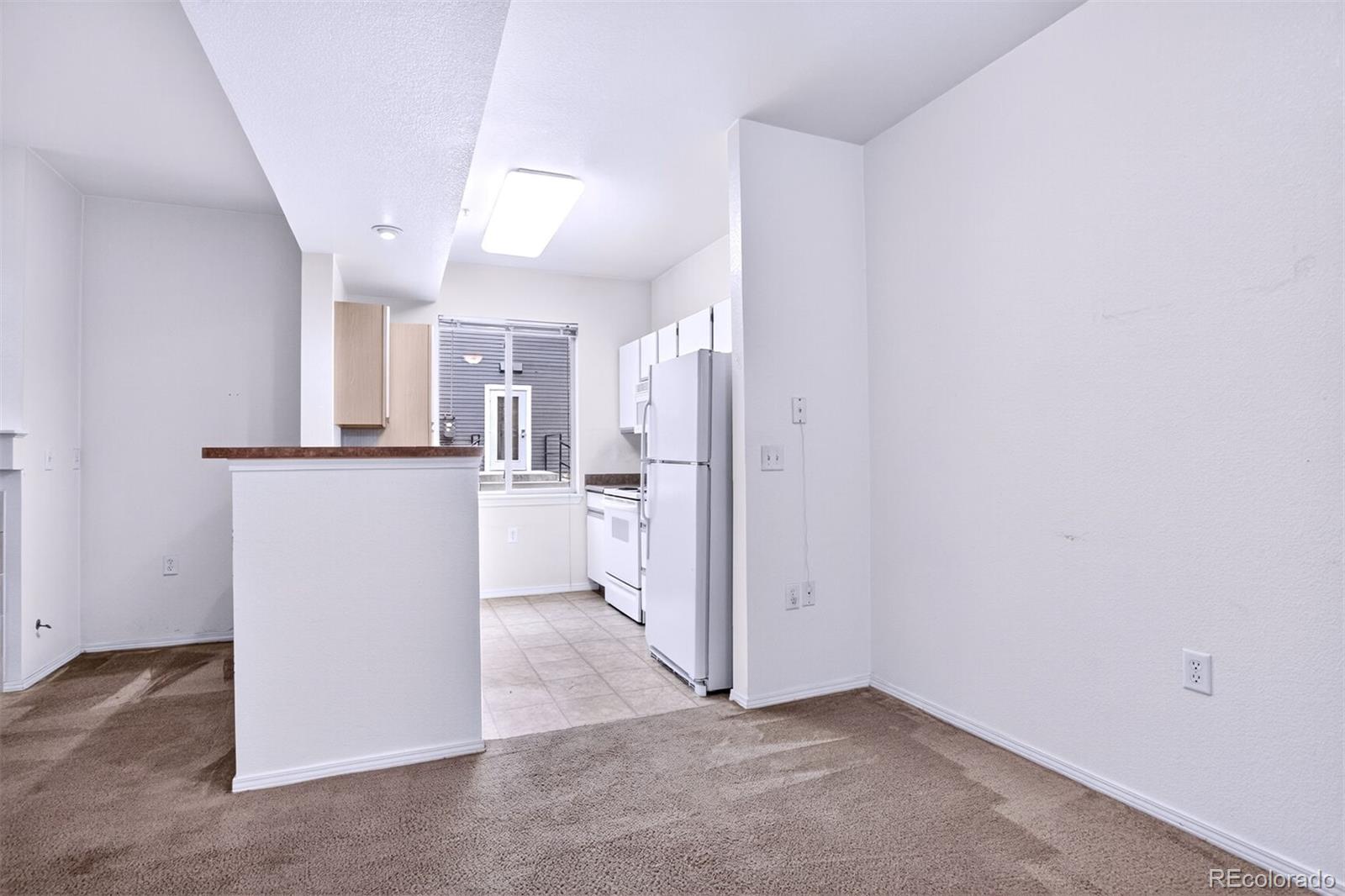 5320 Allison Street, Unit 106 Arvada, CO 80002 - Photo 5 of 15 a view of a kitchen with refrigerator and white cabinets