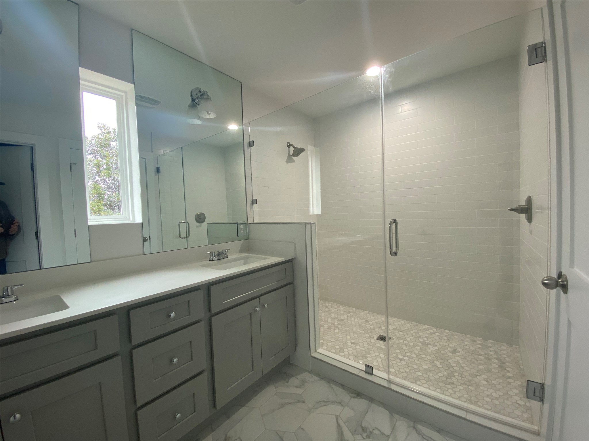 1916 Webberville Road, Unit B Austin, TX 78721 - Photo 17 of 25 Bathroom featuring a dual vanity with light gray cabinetry and white countertops, a large walk-in shower with a frameless glass enclosure, white subway tile walls, and a pebble tile shower floor