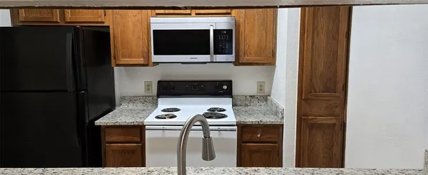 a kitchen with stainless steel appliances granite countertop a stove refrigerator and microwave