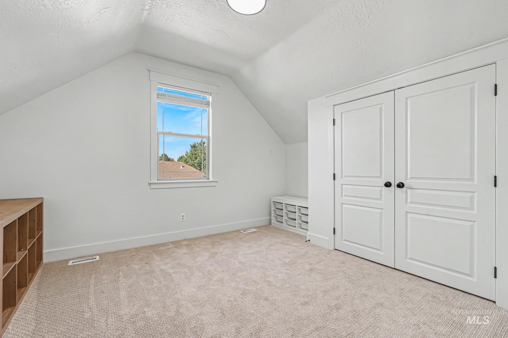 2340 South Alaska Way Meridian, ID 83642 - Photo 28 of 48 Carpeted floor with sloped ceilings, featuring a ceiling fan and a mounted television