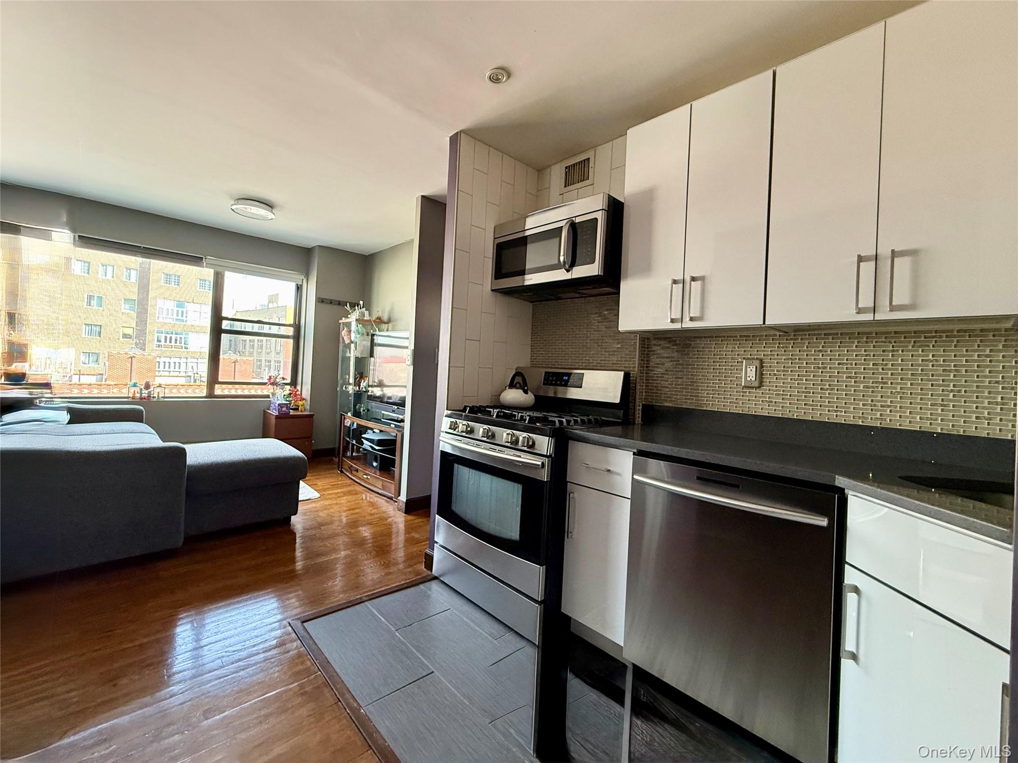 87-14 57th Road, Unit 5A Queens, NY 11373 - Photo 8 of 34 a kitchen with stainless steel appliances granite countertop a stove a sink and a microwave