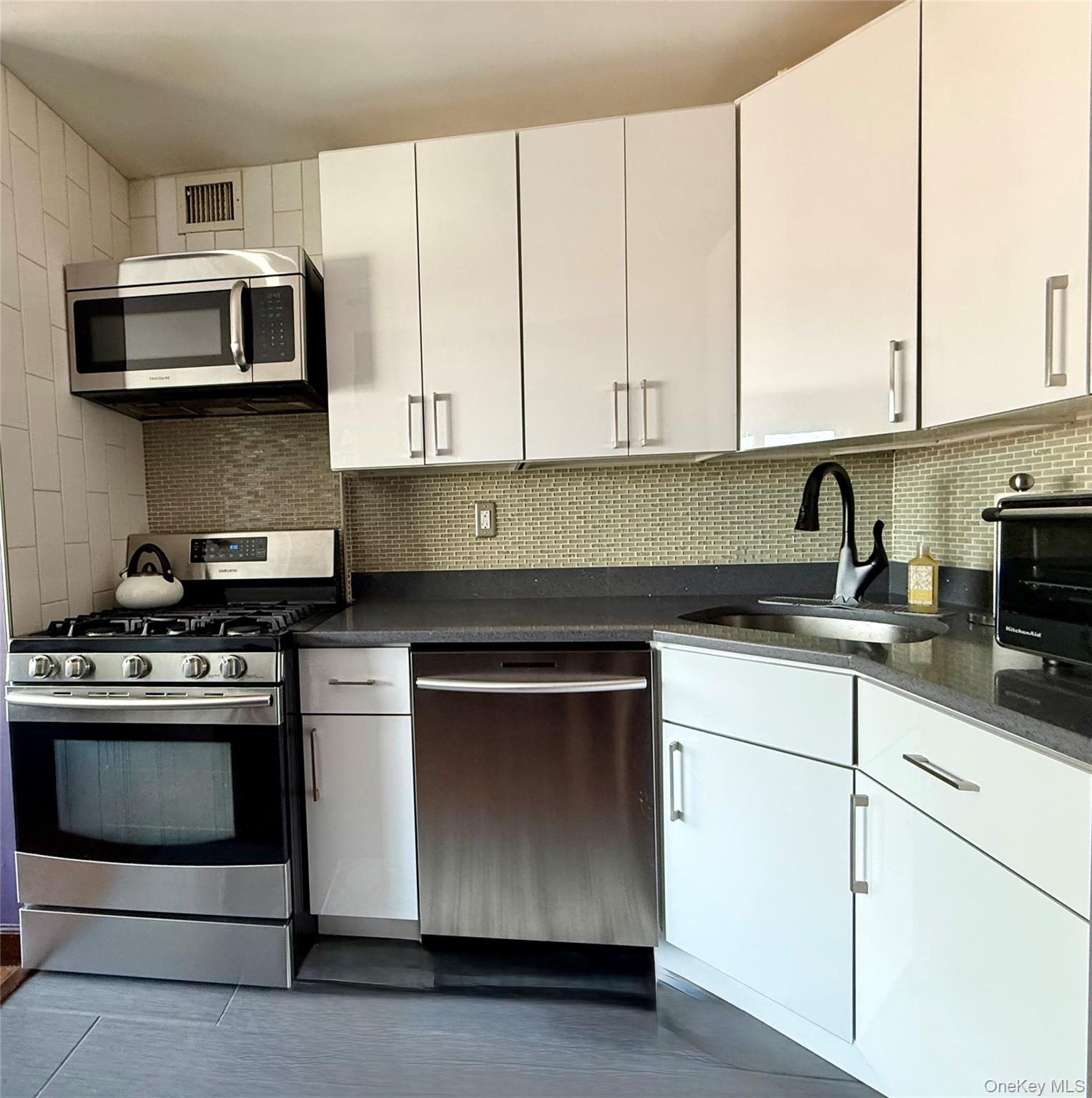 87-14 57th Road, Unit 5A Queens, NY 11373 - Photo 9 of 34 a kitchen with stainless steel appliances granite countertop a sink and a stove