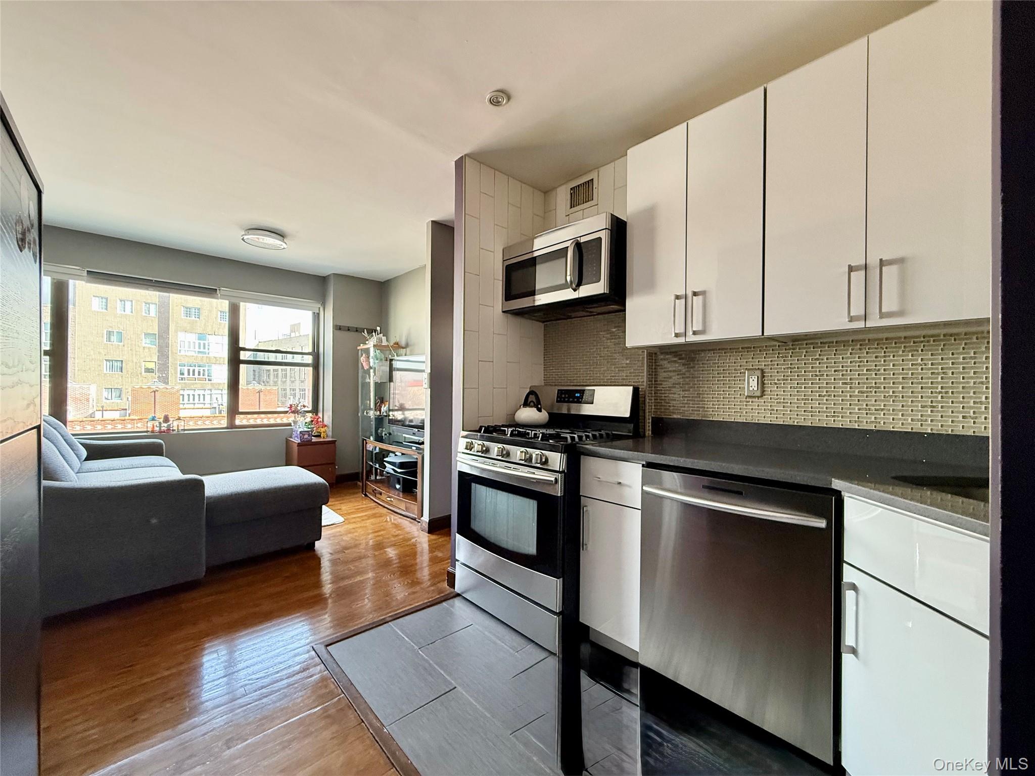 87-14 57th Road, Unit 5A Queens, NY 11373 - Photo 32 of 34 a kitchen with stainless steel appliances granite countertop a stove a sink and white cabinets