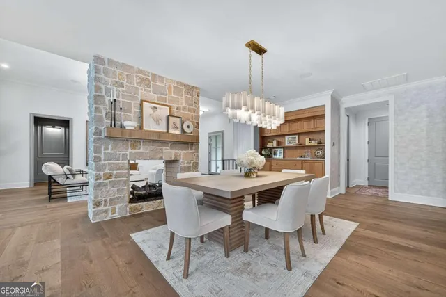 a kitchen with stainless steel appliances granite countertop a stove a sink a oven a dining table with white cabinets and wooden floor