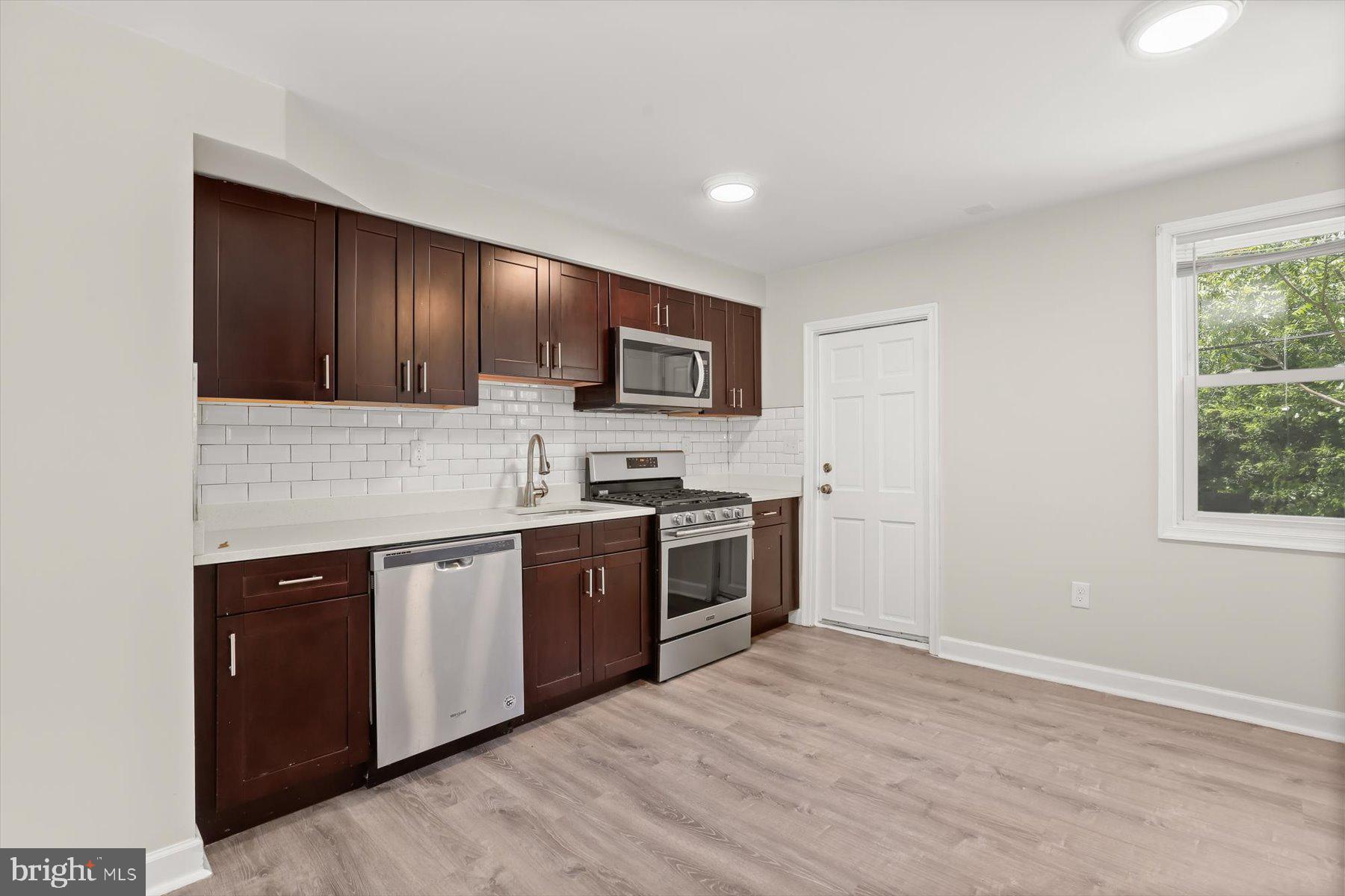 1044 Ellicott Driveway Baltimore, MD 21216 - Photo 6 of 26 a kitchen with stainless steel appliances granite countertop a stove top oven a sink dishwasher and a microwave oven with wooden floor