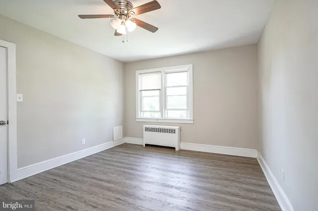 an empty room with wooden floor windows and ceiling fan