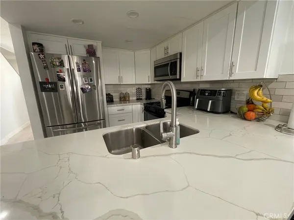 a kitchen with stainless steel appliances a sink a refrigerator a microwave and cabinets