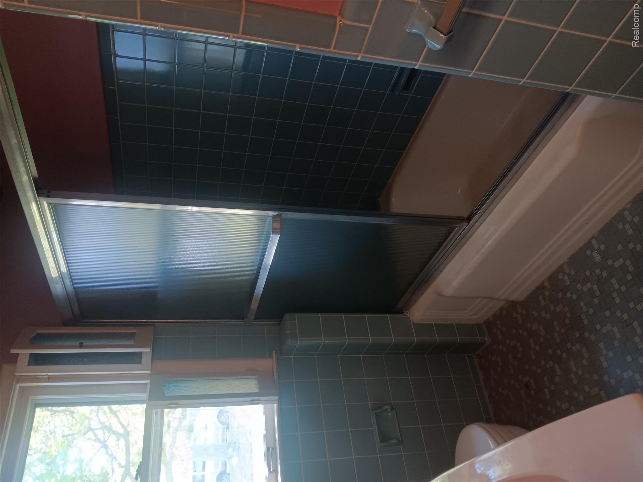 967 Washington Road Grosse Pointe, MI 48230 - Photo 11 of 15 Full bathroom featuring combined bath / shower with glass door, vanity, healthy amount of natural light, and tile walls