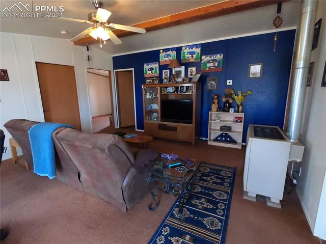 609 3rd Avenue Romeo, CO 81148 - Photo 2 of 16 Living room with dark colored carpet, ceiling fan, and vaulted ceiling with beams