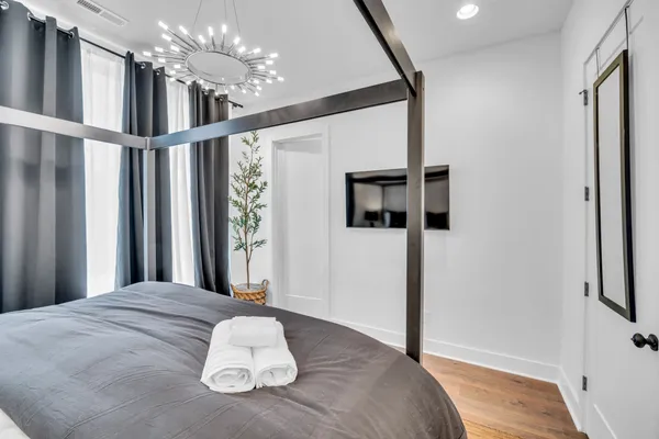 a view of a bedroom with wooden floor and a chandelier