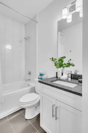 a bathroom with a granite countertop sink a toilet a mirror and bathtub