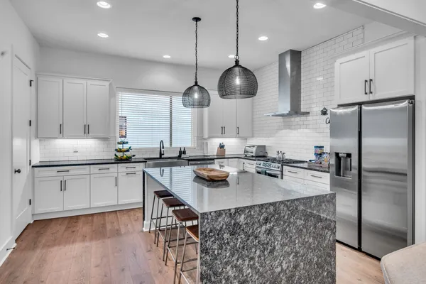 a kitchen with a sink a center island stainless steel appliances and cabinets