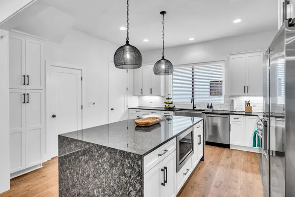 a kitchen with stainless steel appliances granite countertop a sink a stove and a wooden floor