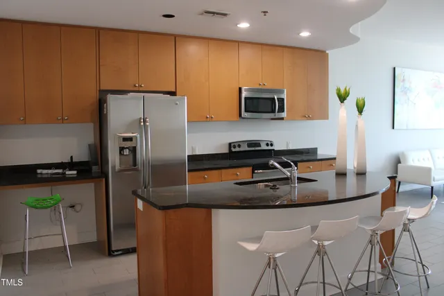 a kitchen with stainless steel appliances granite countertop a refrigerator a stove a microwave a sink and chairs