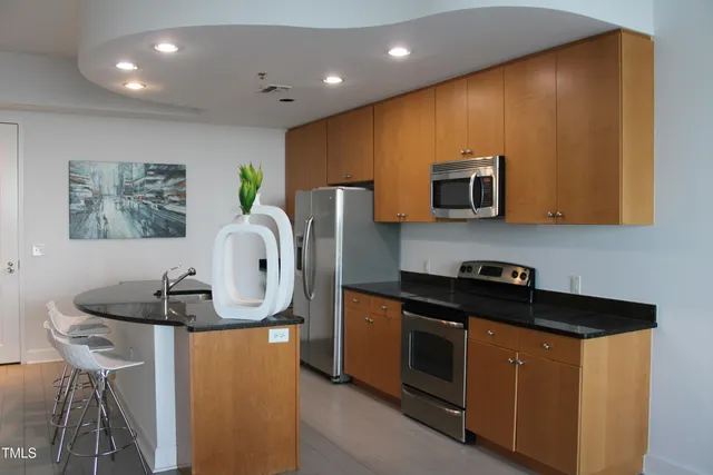 a kitchen with stainless steel appliances granite countertop a sink a stove a microwave a counter top and a cabinets