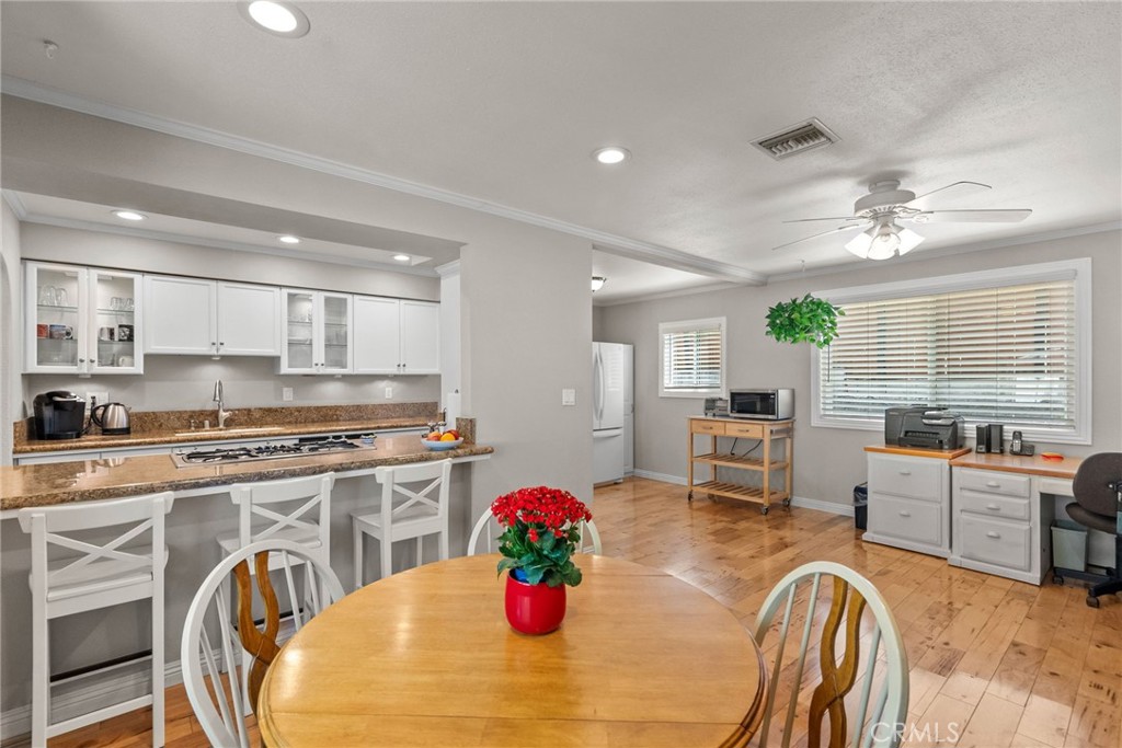 26450 Ridge Vale Drive Newhall, CA 91321 - Photo 15 of 40 a kitchen with stainless steel appliances granite countertop a stove top oven a dining table and chairs with white cabinets