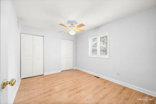 an empty room with windows and ceiling fan