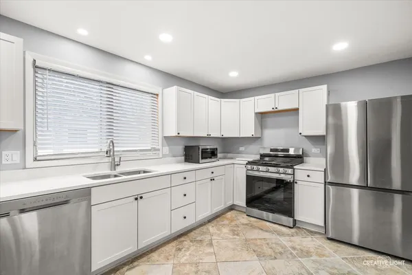 a kitchen with a sink stainless steel appliances and window