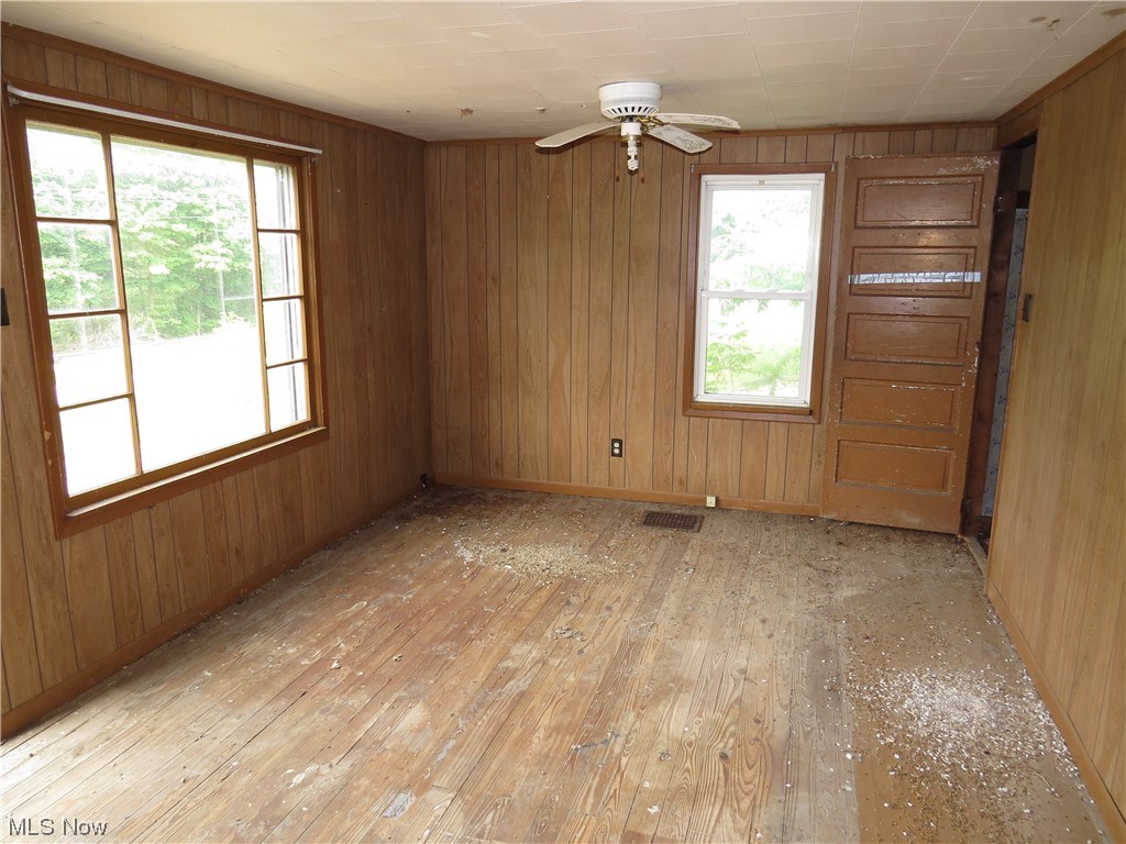 1054 Bergholz Road Southeast Bergholz, OH 43908 - Photo 4 of 11 Empty room featuring light wood-type flooring, wood walls, and ceiling fan