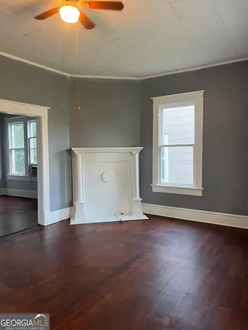 an empty room with wooden floor cabinet and windows
