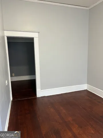 a view of an empty room with wooden floor and closet
