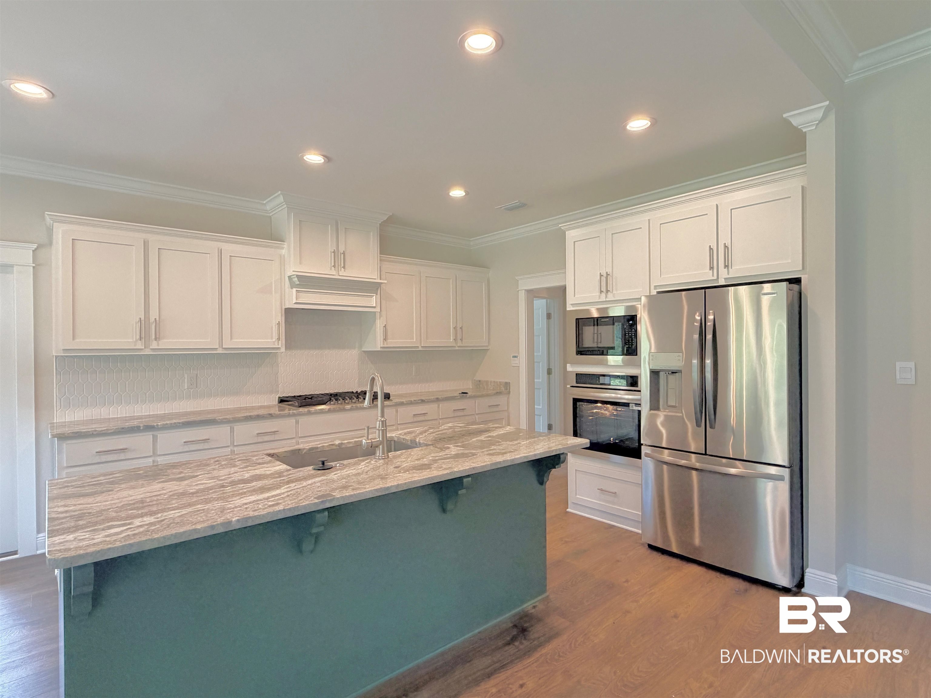 318 Morning Mist Way Fairhope, AL 36532 - Photo 4 of 20 Kitchen featuring a contrasting island with an undermount sink, stainless steel appliances, white shaker cabinetry, and wood-finish flooring