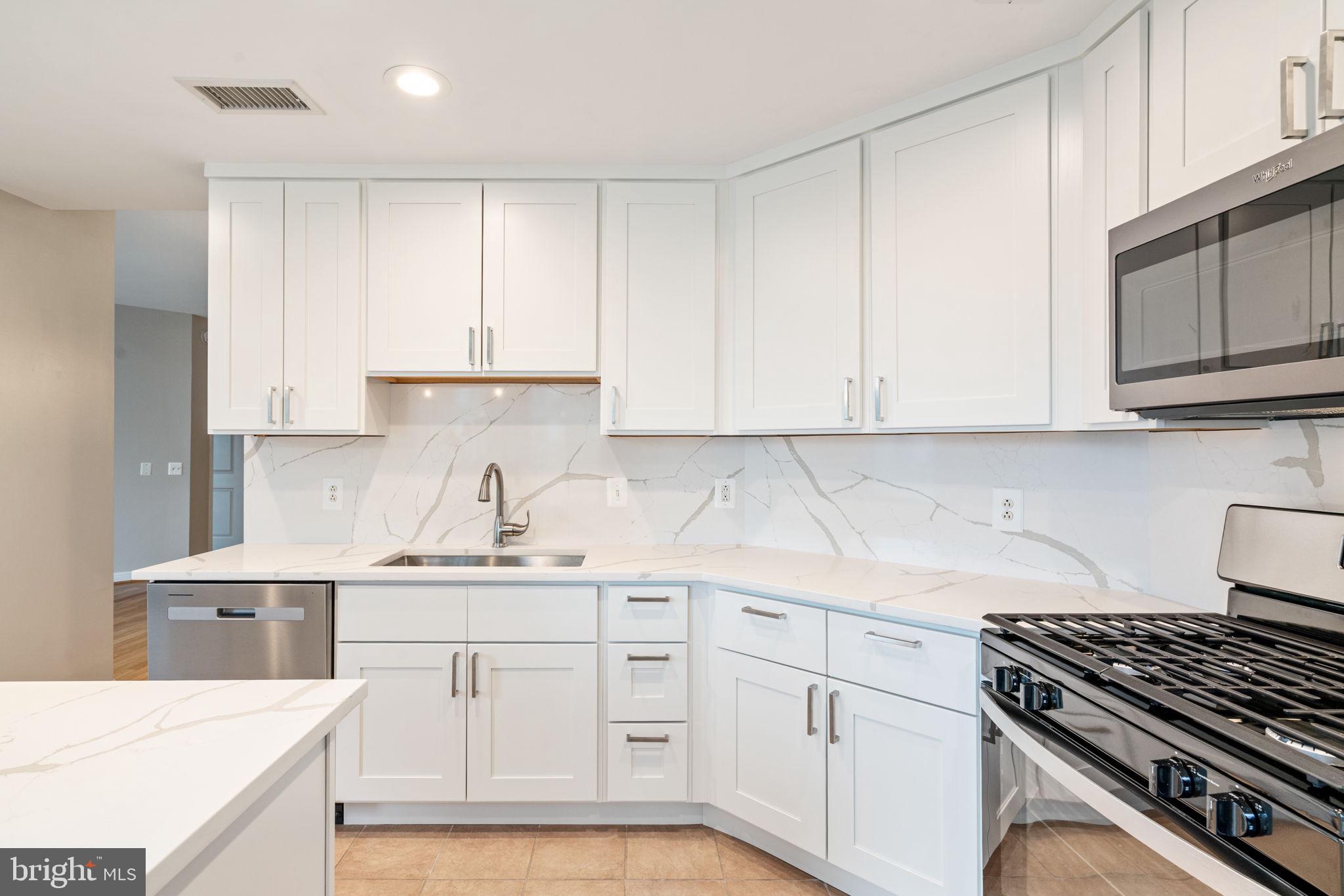 11990 Market Street, Unit 1311 Reston, VA 20190 - Photo 32 of 59 a kitchen with cabinets appliances a sink and a counter top space