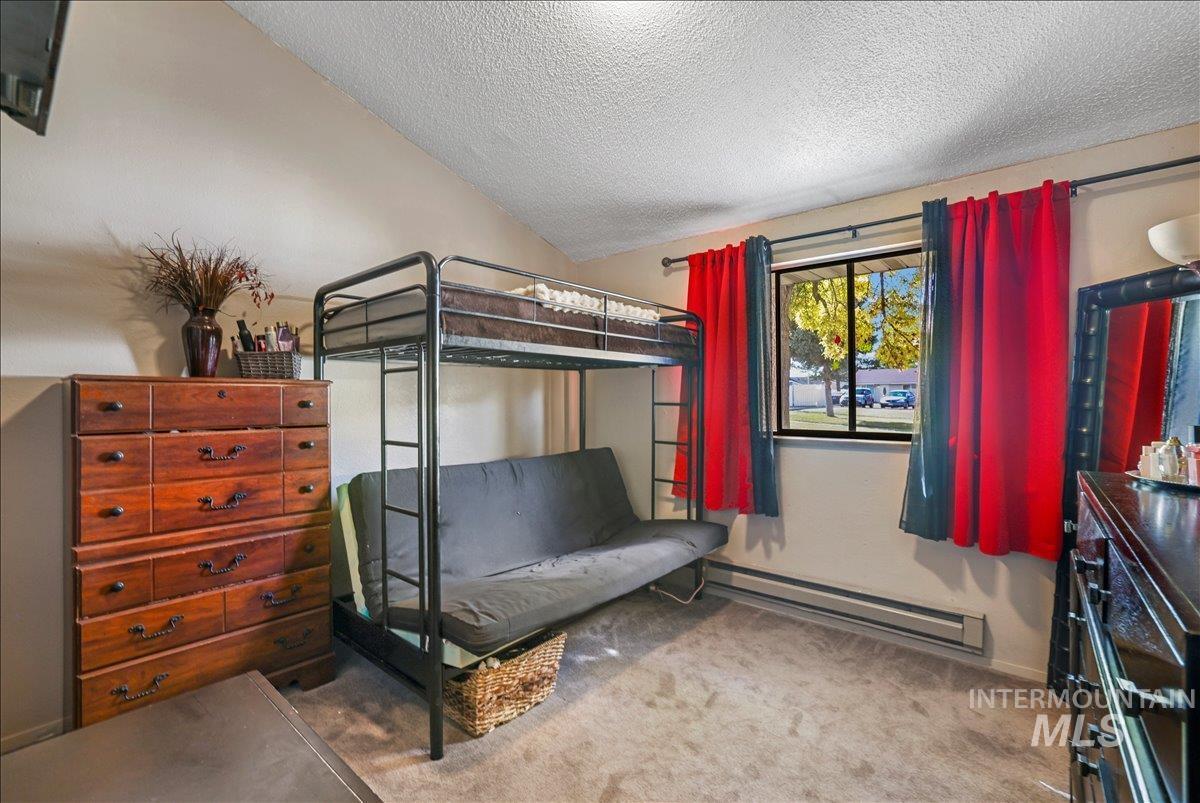 259 Pheasant Road West, Unit 2 Twin Falls, ID 83301 - Photo 14 of 31 Bedroom featuring a baseboard heating unit, light colored carpet, a textured ceiling, and lofted ceiling