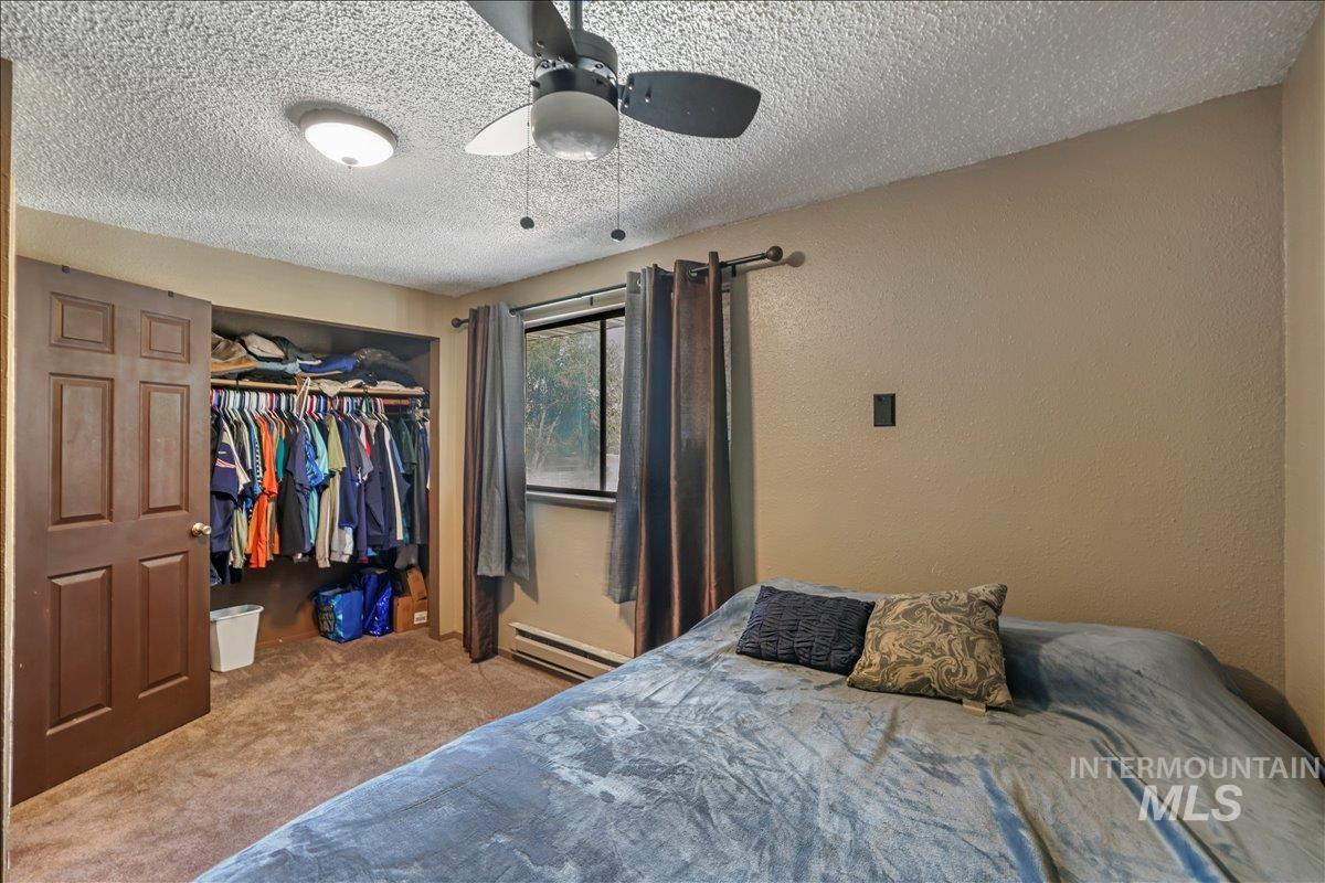 259 Pheasant Road West, Unit 2 Twin Falls, ID 83301 - Photo 23 of 31 Carpeted bedroom with a textured ceiling, a closet, baseboard heating, ceiling fan, and a textured wall