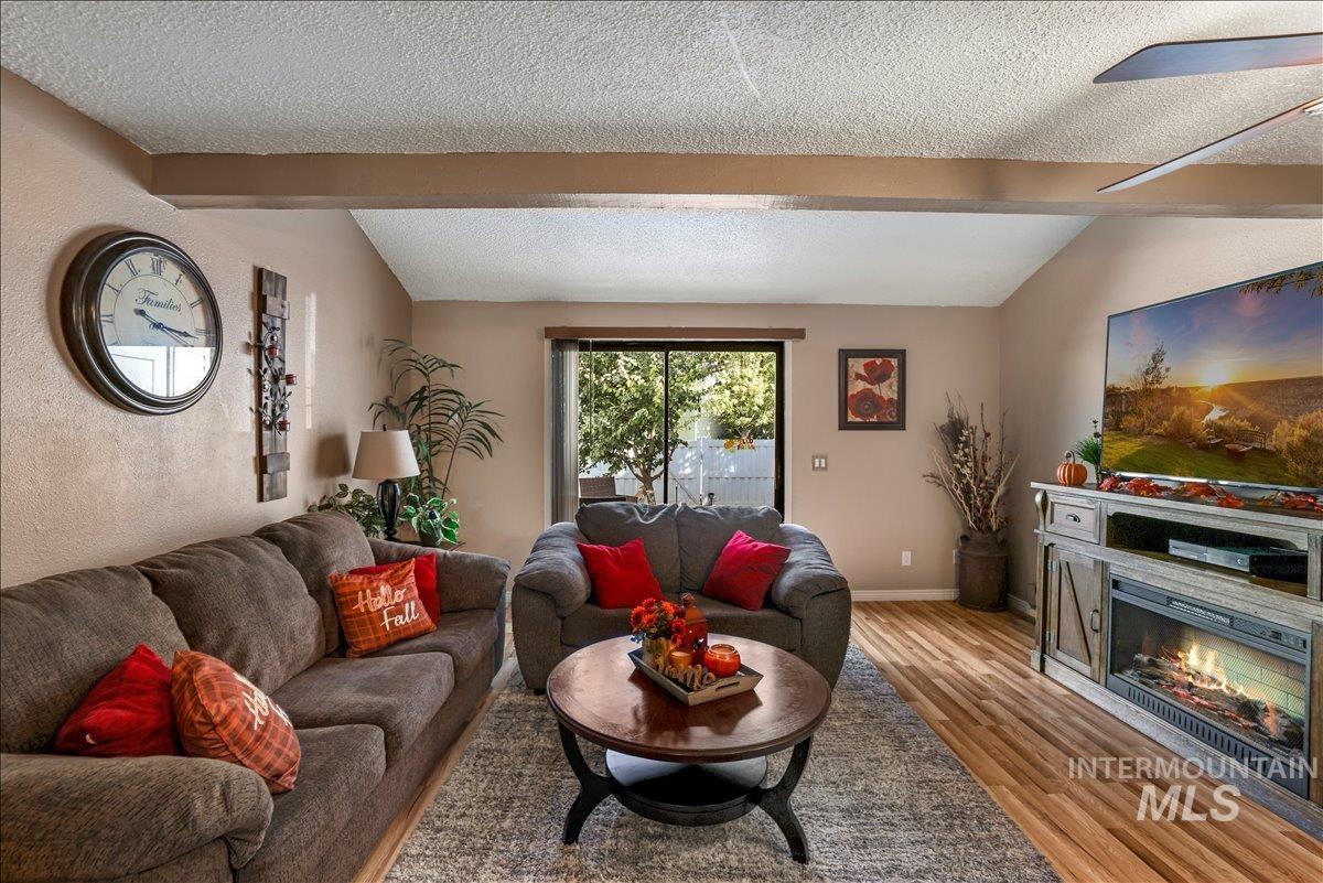 259 Pheasant Road West, Unit 2 Twin Falls, ID 83301 - Photo 9 of 31 Living room with a textured ceiling, light wood-style flooring, a glass covered fireplace, and a textured wall
