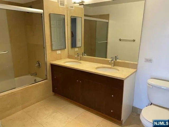 a bathroom with a double vanity sink toilet mirror and bathtub